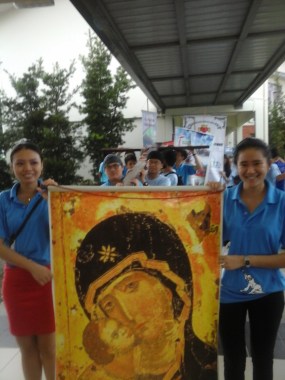 Olivia (right) and other St Simon Church youths posing with the portrait of the Blessed Mother Mary and Child Jesus. The SYD Cross is seen in the background. 